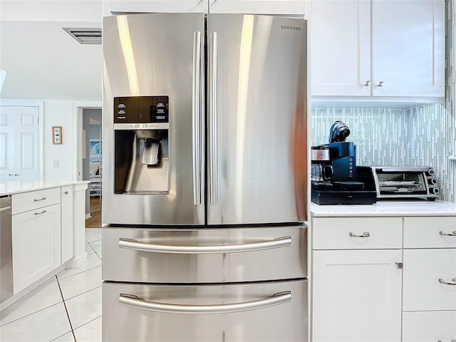 kitchen featuring light tile patterned floors, backsplash, white cabinets, and appliances with stainless steel finishes