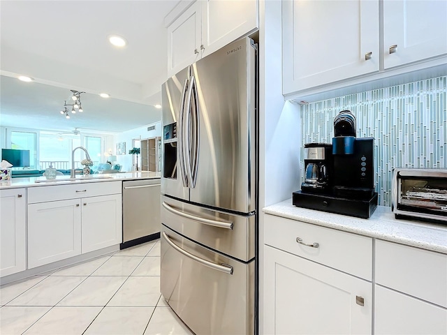 kitchen featuring light tile patterned flooring, appliances with stainless steel finishes, white cabinetry, sink, and decorative backsplash