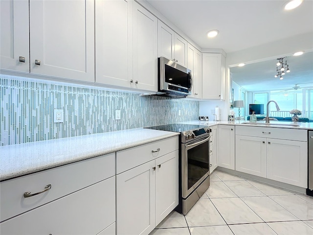 kitchen featuring sink, stainless steel appliances, tasteful backsplash, white cabinets, and light tile patterned flooring