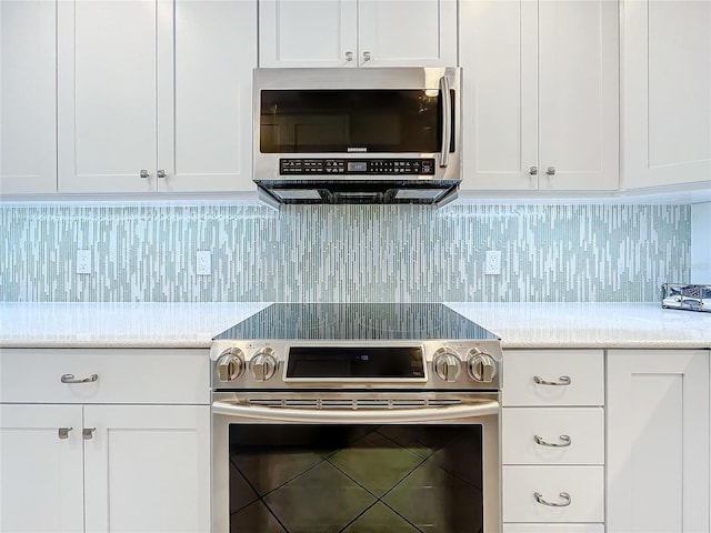 kitchen featuring stainless steel appliances, white cabinets, and backsplash