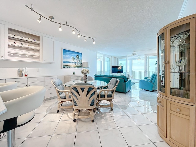 dining area with light tile patterned flooring, ceiling fan, and a textured ceiling