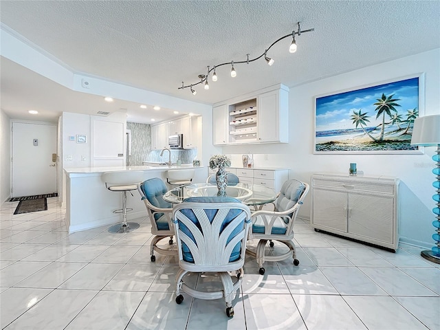 tiled dining area with a textured ceiling