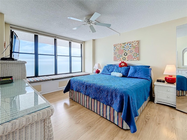 bedroom featuring ceiling fan, a textured ceiling, and light hardwood / wood-style flooring