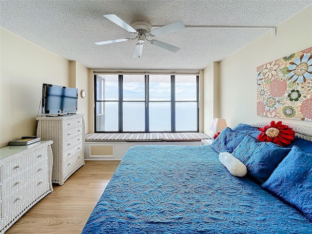 bedroom featuring ceiling fan, light hardwood / wood-style flooring, and a textured ceiling