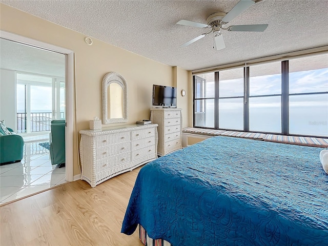 bedroom featuring ceiling fan, a textured ceiling, and light wood-type flooring