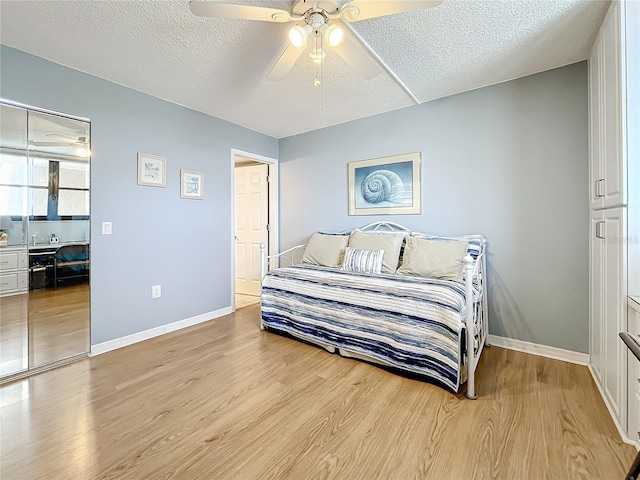 bedroom featuring ceiling fan, light hardwood / wood-style floors, and a textured ceiling