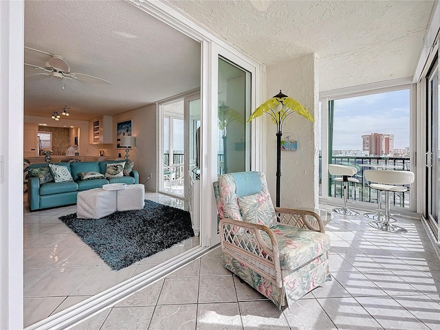 living room with ceiling fan, light tile patterned floors, and a textured ceiling