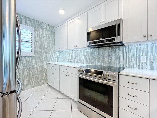 kitchen with white cabinetry, tasteful backsplash, light tile patterned flooring, and appliances with stainless steel finishes