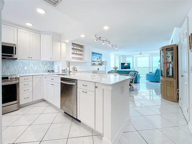 kitchen with sink, light tile patterned floors, appliances with stainless steel finishes, white cabinetry, and kitchen peninsula