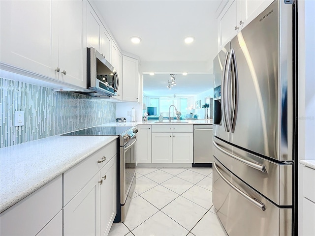 kitchen with sink, white cabinetry, tasteful backsplash, light tile patterned floors, and appliances with stainless steel finishes