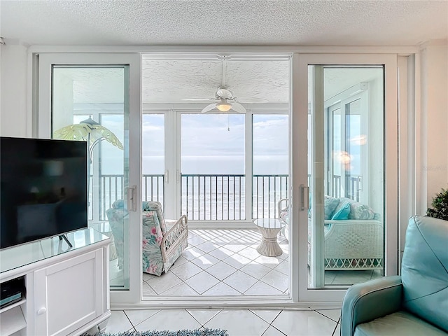 entryway with a water view, ceiling fan, a textured ceiling, and light tile patterned floors