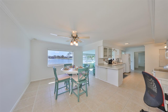 dining space with ceiling fan, a water view, light tile patterned flooring, and ornamental molding