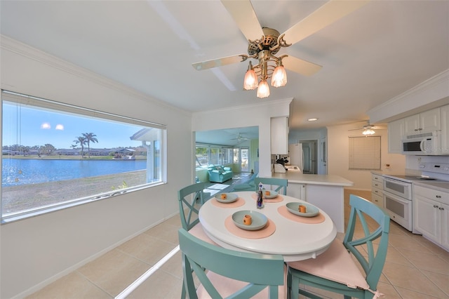 dining space featuring light tile patterned flooring, a water view, crown molding, and ceiling fan