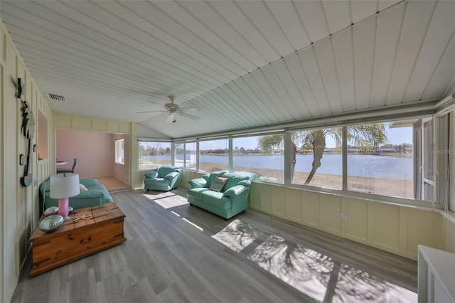 sunroom / solarium featuring a water view, vaulted ceiling, ceiling fan, and a healthy amount of sunlight