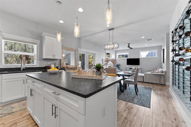 kitchen with white cabinetry, a kitchen island, sink, and decorative light fixtures