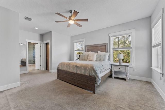 bedroom featuring multiple windows, ceiling fan, light colored carpet, and a textured ceiling