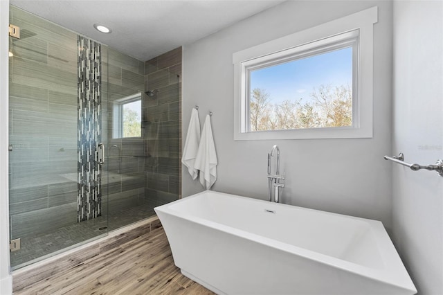 bathroom featuring a healthy amount of sunlight, hardwood / wood-style floors, and separate shower and tub