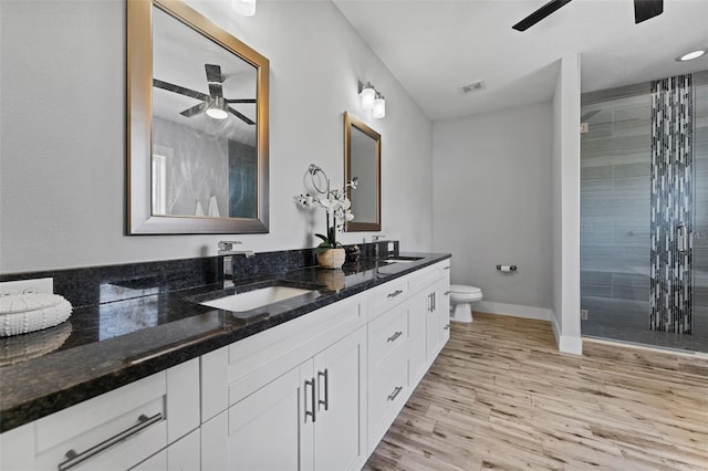 bathroom with toilet, a shower with shower door, vanity, ceiling fan, and hardwood / wood-style floors