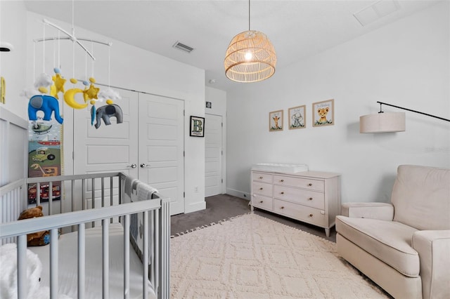 bedroom with carpet floors, a crib, and a closet