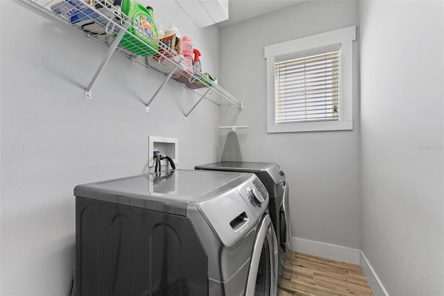 washroom with washing machine and dryer and light wood-type flooring