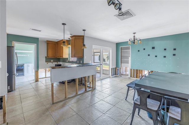 kitchen featuring stainless steel refrigerator, a chandelier, hanging light fixtures, and light tile patterned floors