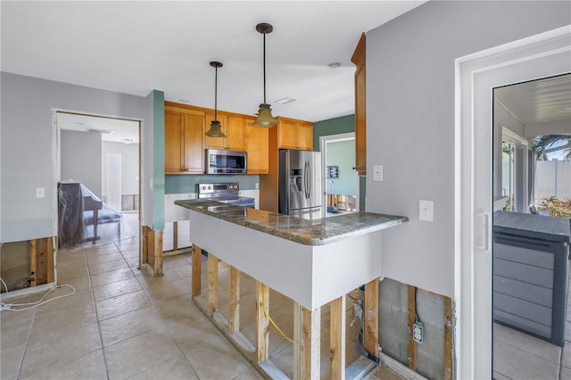 kitchen with a breakfast bar, stainless steel appliances, decorative light fixtures, kitchen peninsula, and dark stone counters