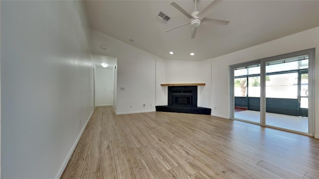 unfurnished living room with ceiling fan, a brick fireplace, and light wood-type flooring