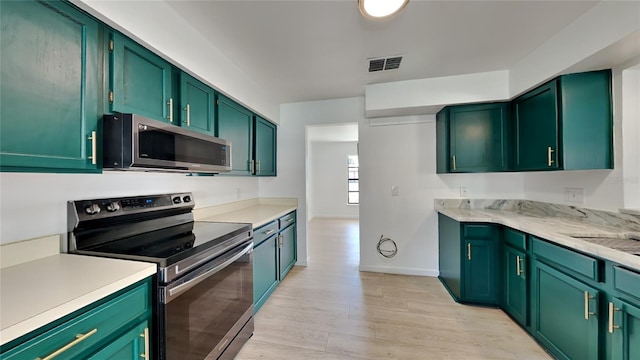 kitchen featuring appliances with stainless steel finishes, sink, light hardwood / wood-style flooring, and green cabinetry