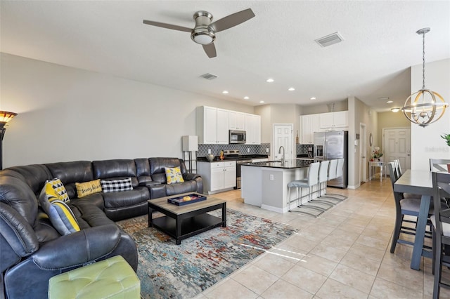 living room featuring ceiling fan with notable chandelier, sink, a textured ceiling, and light tile patterned floors