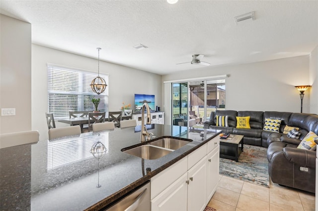 kitchen featuring sink, dark stone counters, hanging light fixtures, and white cabinets