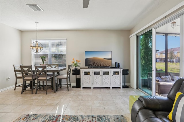 living room featuring light tile patterned floors, ceiling fan with notable chandelier, and a textured ceiling