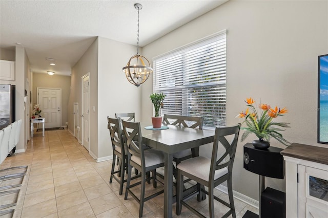 dining area with an inviting chandelier, light tile patterned floors, and a textured ceiling