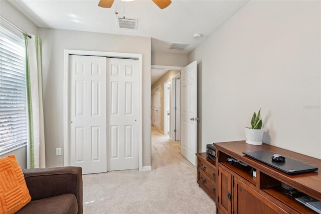 living area with light carpet and ceiling fan