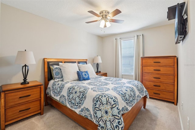 carpeted bedroom featuring ceiling fan and a textured ceiling