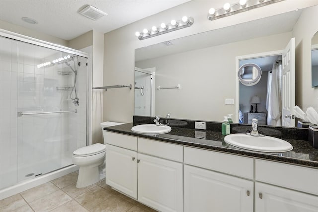 bathroom featuring toilet, an enclosed shower, a textured ceiling, vanity, and tile patterned flooring