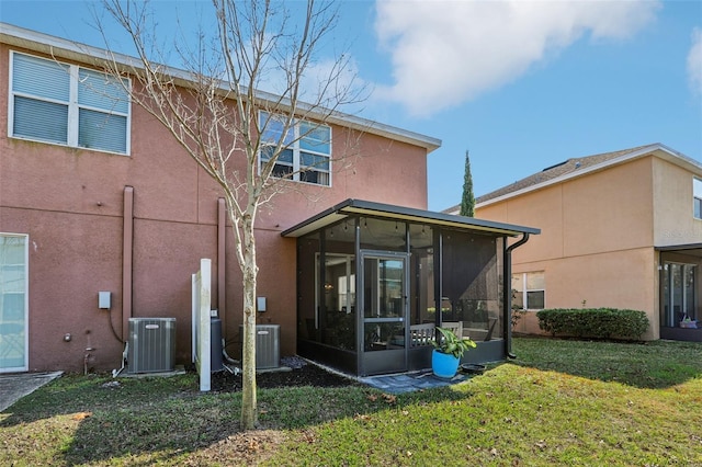 rear view of house with a sunroom, central AC, and a lawn