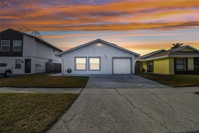 single story home featuring a garage and a lawn