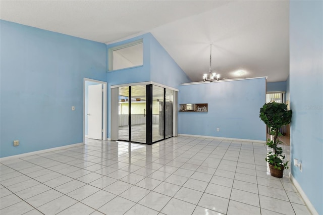 tiled spare room with an inviting chandelier, a wealth of natural light, and high vaulted ceiling