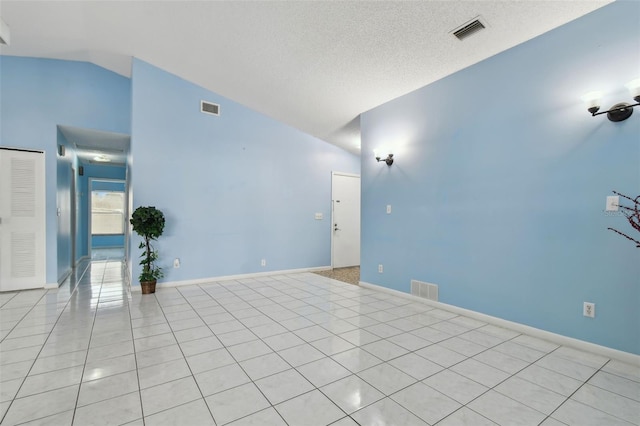 unfurnished room featuring lofted ceiling, light tile patterned floors, and a textured ceiling