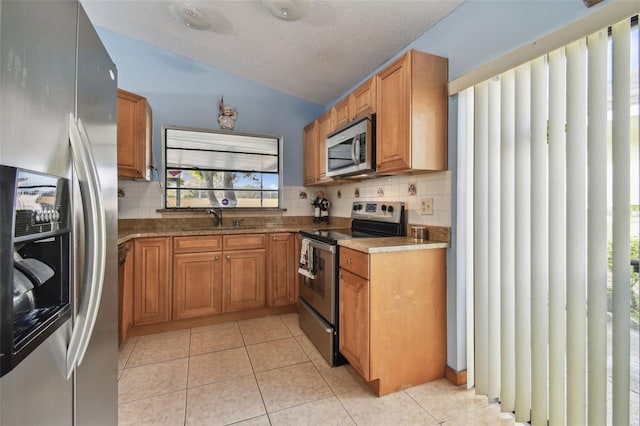 kitchen with light tile patterned floors, sink, appliances with stainless steel finishes, decorative backsplash, and vaulted ceiling