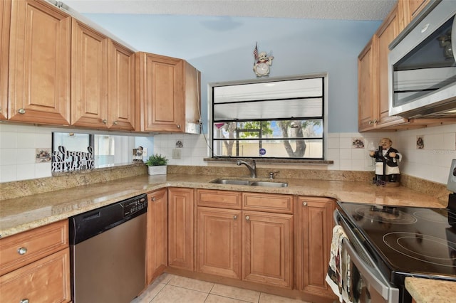 kitchen with sink, decorative backsplash, light tile patterned floors, light stone counters, and stainless steel appliances