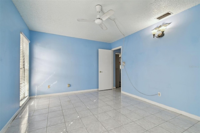 tiled spare room with a textured ceiling and ceiling fan