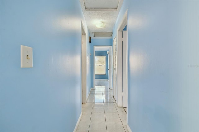 hallway featuring light tile patterned floors and a textured ceiling