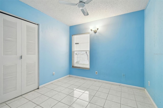 unfurnished bedroom featuring ceiling fan, light tile patterned floors, a textured ceiling, and a closet