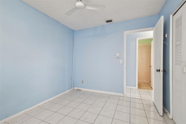 tiled spare room with a textured ceiling and ceiling fan