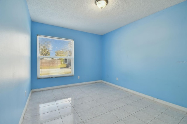 empty room with a textured ceiling and light tile patterned flooring