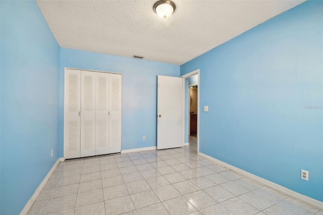 unfurnished bedroom with light tile patterned floors, a closet, and a textured ceiling