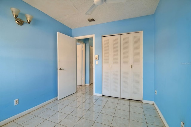 unfurnished bedroom with light tile patterned floors, a textured ceiling, ceiling fan, and a closet