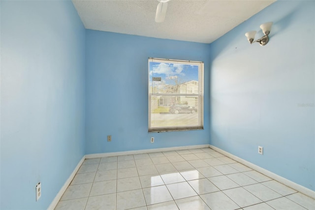 empty room featuring ceiling fan, light tile patterned floors, and a textured ceiling