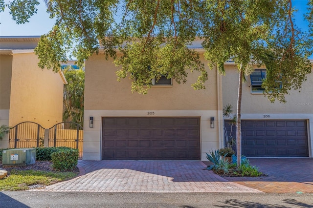 view of front of house with decorative driveway, an attached garage, and stucco siding